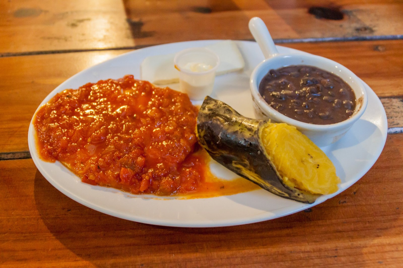 Desayuno guatemalteco: Huevos rancheros con salsa de tomate o chirmol, acompañados de frijoles negros parados, y un platano cocido.